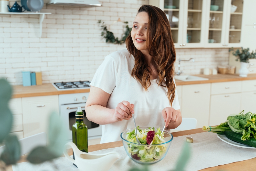 Plus sized woman on weight loss journey preparing a healthy salad to eat mindfully.